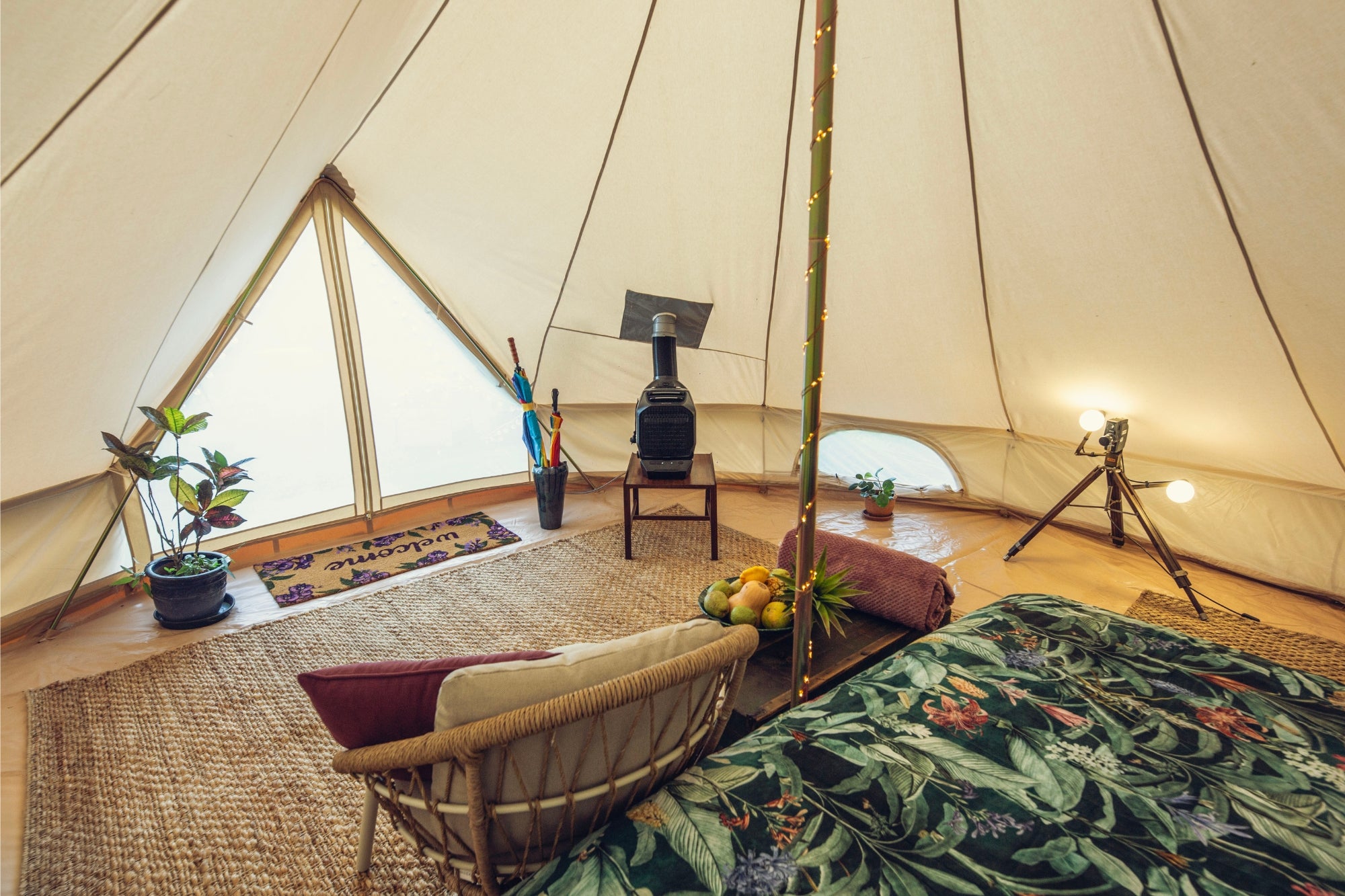 6m bell tent interior with wood stove, rugs, seating area, and warm lighting for comfortable camping