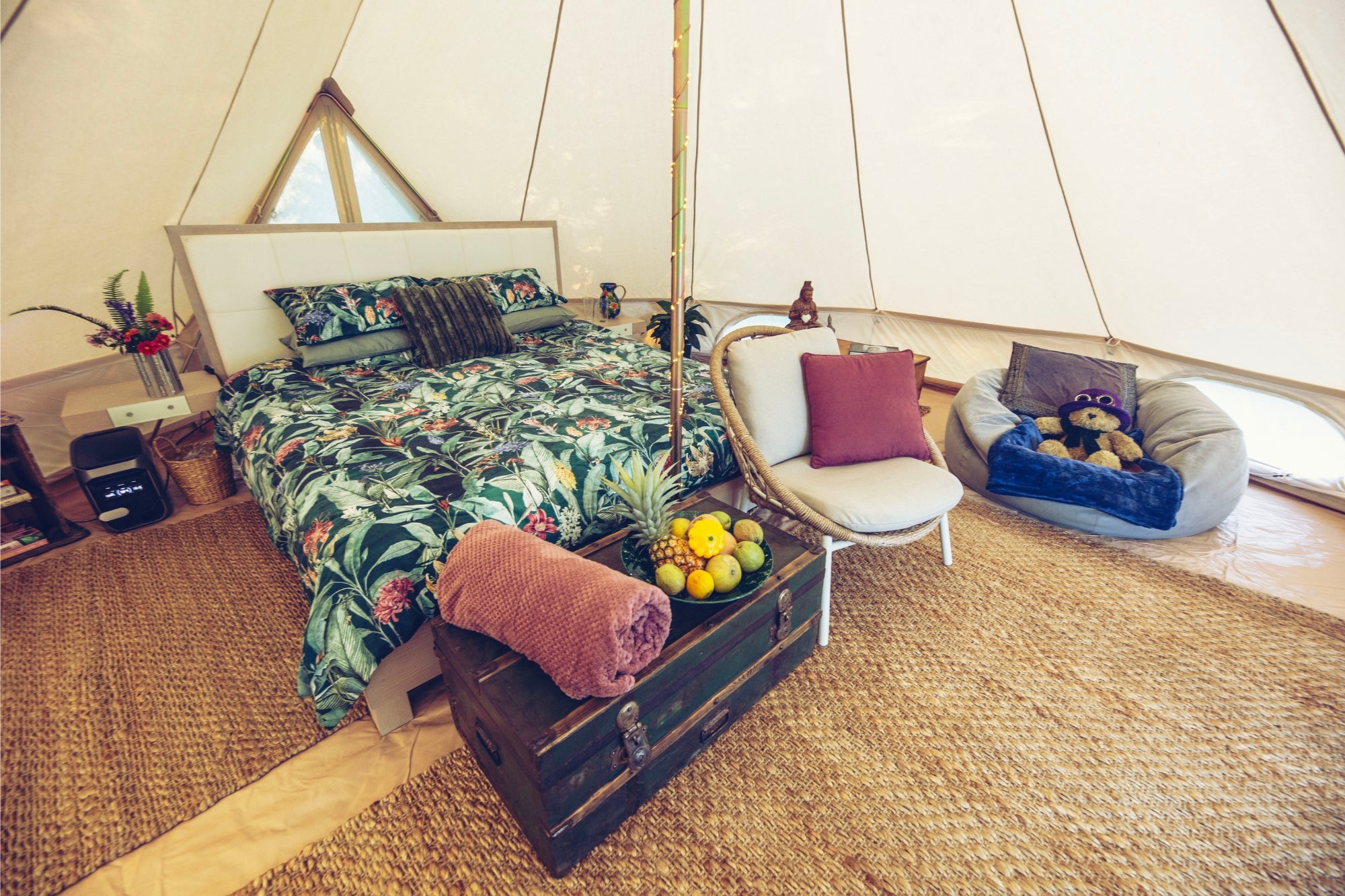6m luxury bell tent interior with double bed, tropical bedding, rugs, and cozy seating for glamping